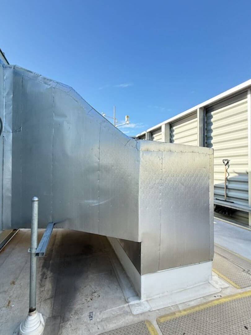 Rooftop HVAC ductwork under clear sky.