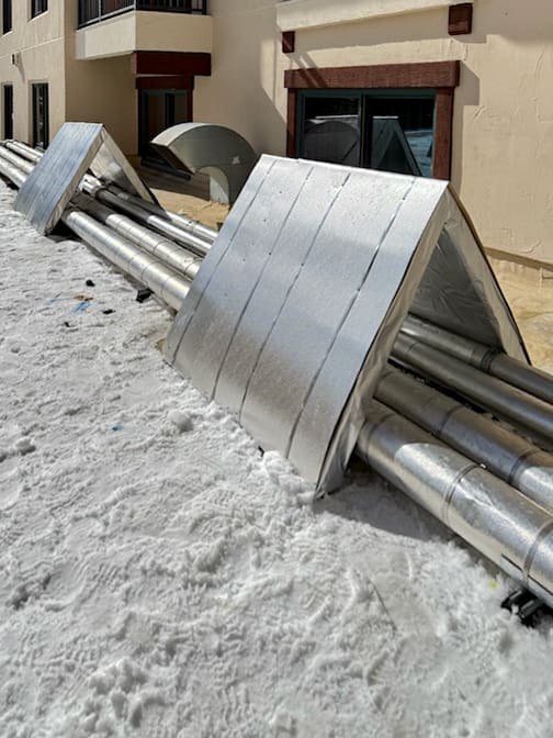 Pipes covered in snow outside building.